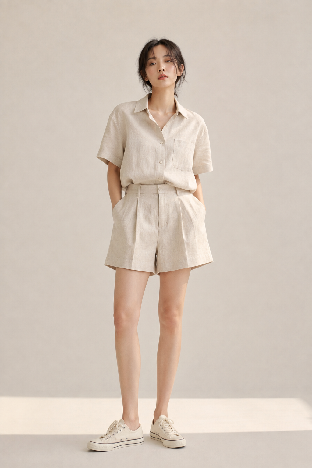 Boxy short-sleeve linen shirt tucked into pleated shorts with canvas sneakers, an easy smart-casual summer acubi fit.