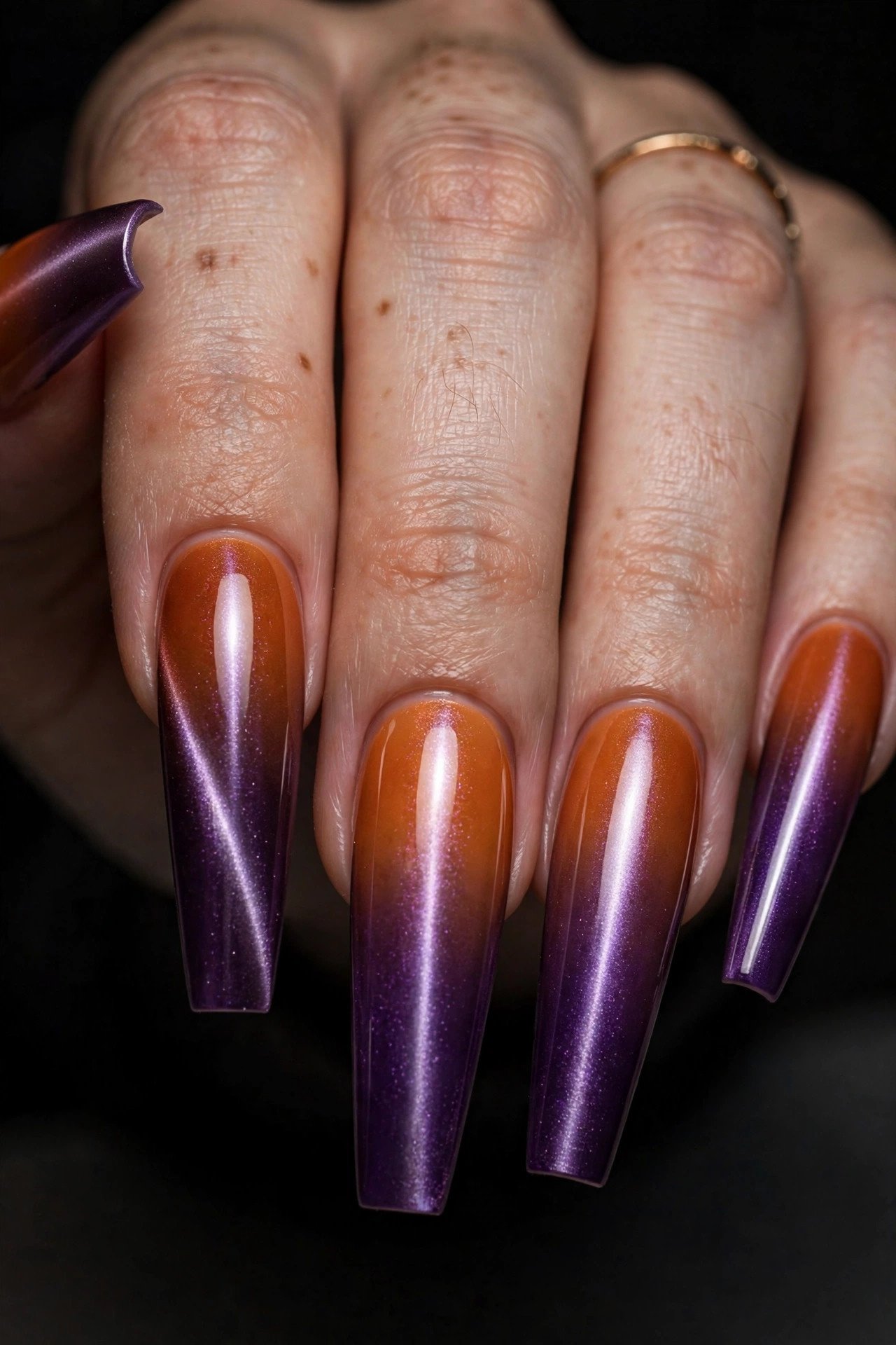 Close-up of coffin nails with an orange to deep purple magnetic cat eye ombre gradient with shimmering light play